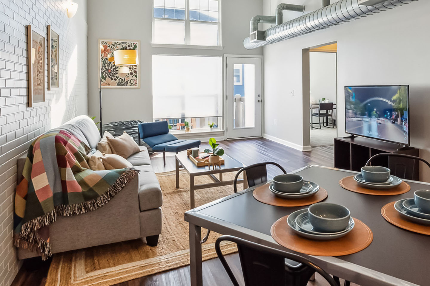Modern stylized apartment with central couch and seating around a TV.
