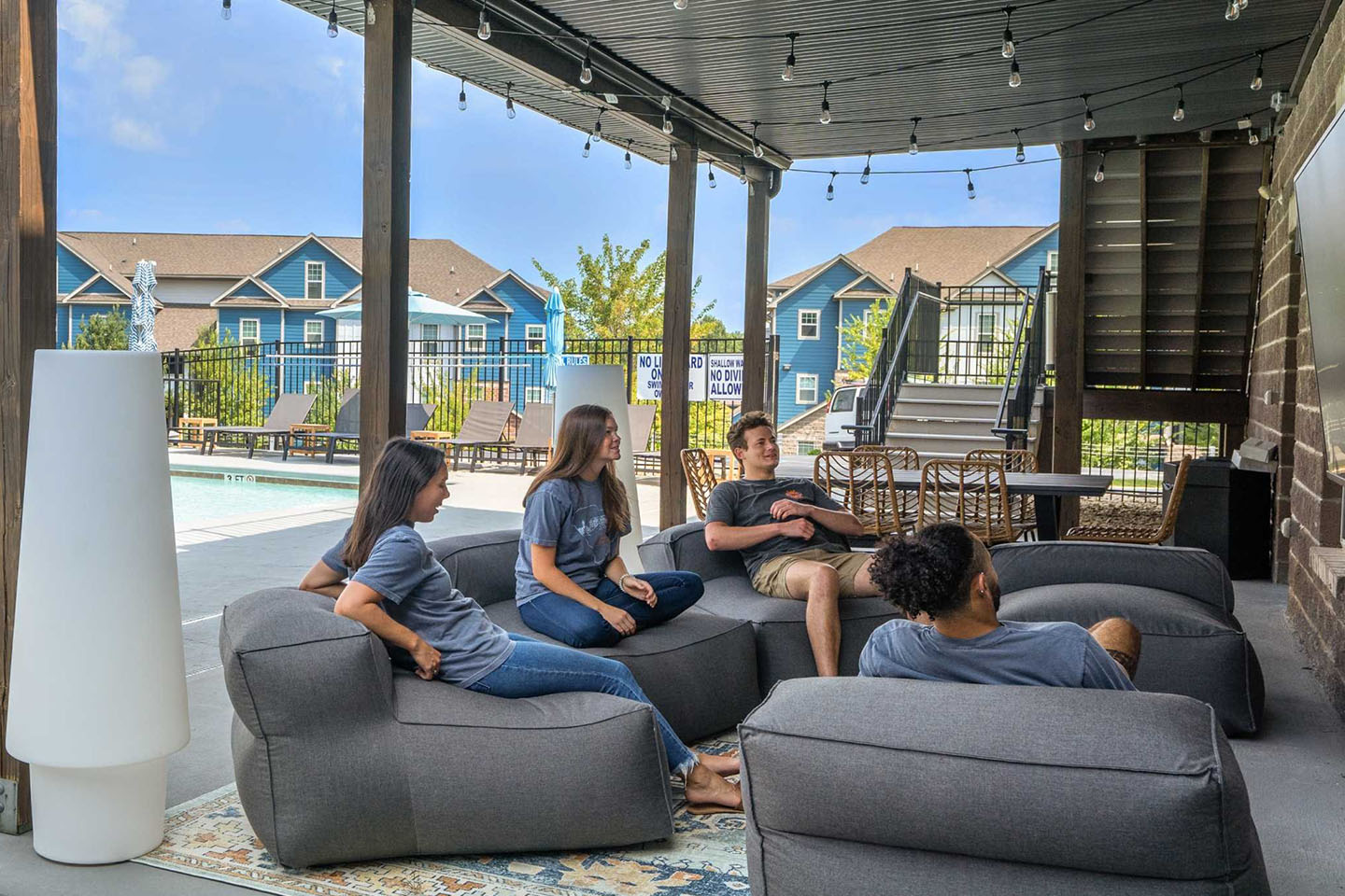 Friends gathered outside in common space watching a show on a large TV.